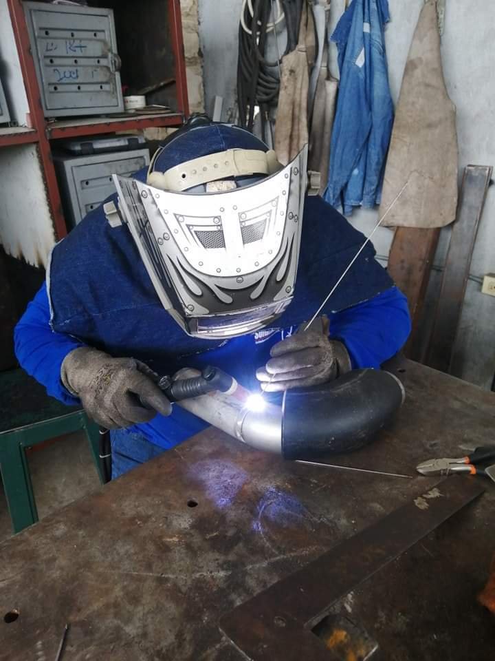 Técnico de MRI realizando soldadura de precisión en taller industrial, con equipo de seguridad adecuado, garantizando la calidad y eficiencia en cada pieza fabricada.