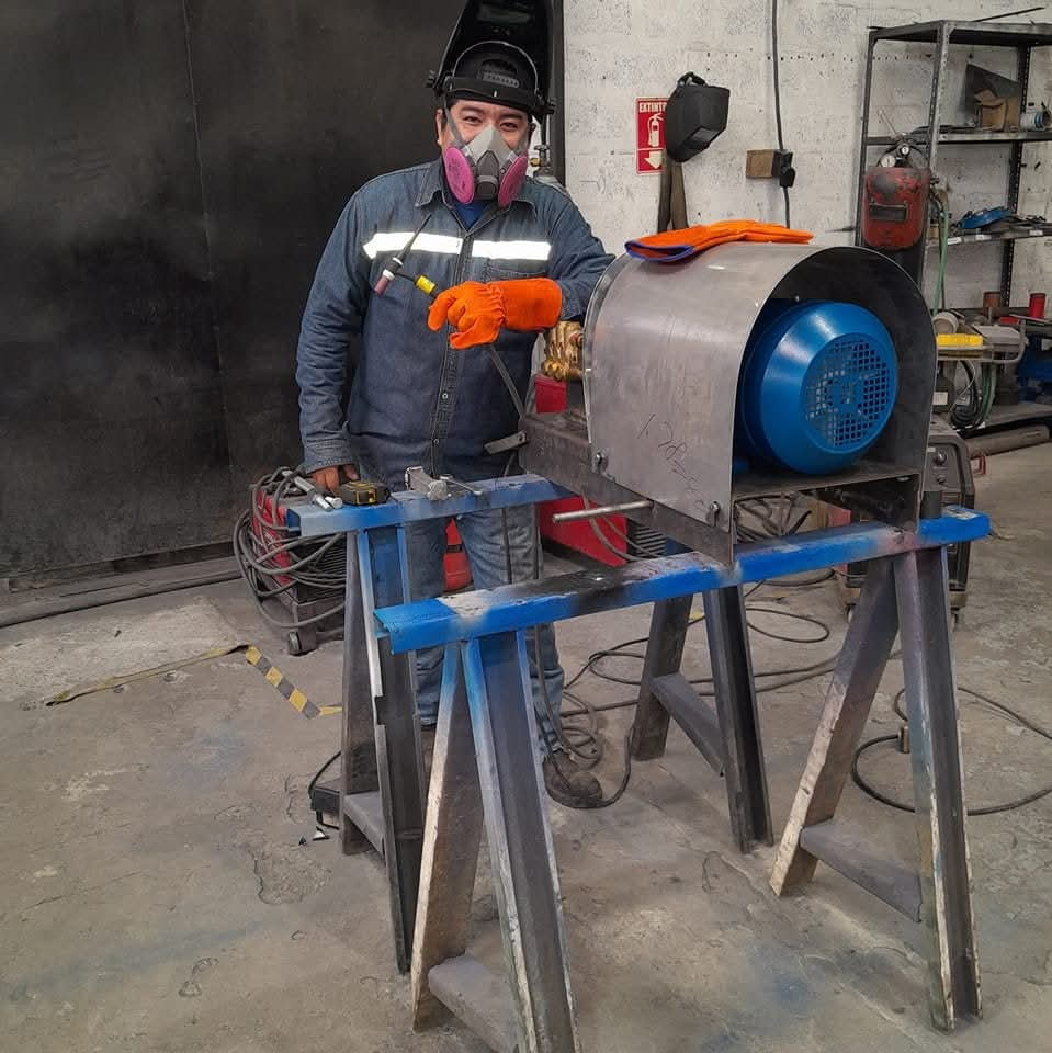 Operario realizando el ensamblaje y alineamiento de una bomba industrial en taller, usando equipo de protección personal para garantizar seguridad durante el proceso.